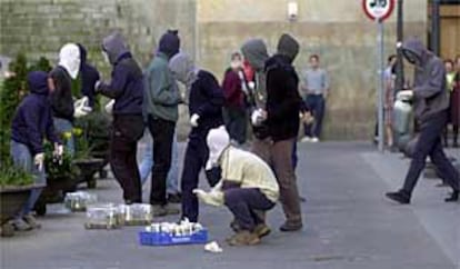 Un grupo de encapuchados prepara bombas incendiarias en una calle de Bilbao para sus acciones de violencia callejera.