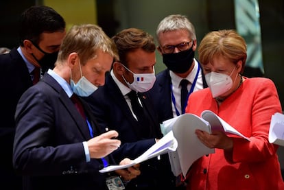 De izquierda a derecha, el presidente del Gobierno español, Pedro Sánchez; el presidente francés, Emmanuel Macron, y la canciller alemana, Angela Merkel, examinan documentos durante la cumbre de la UE en Bruselas el 20 de julio.