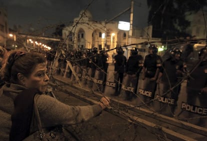 Una mujer sujeta la alambrada que separa a los manifestantes del palacio.