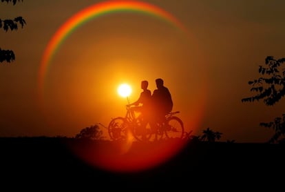 Las siluetas de dos jóvenes junto a sus bicicletas en la localidad india de Agartala, el 21 de noviembre de 2016.