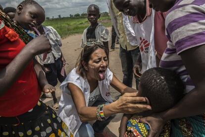 Nuria Balbuena, responsable de la campaña de vacunación, examina a un niño que probablemente tenga sarampión en la puerta del local donde se llevará a cabo la vacunación en Dilukuy.