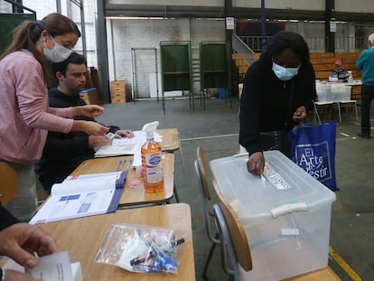 Una mujer deposita su voto en una urna ante la mirada de tres vocales de mesa, en Santiago (Chile), durante el plebiscito constitucional de septiembre de 2022.