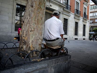 Un hombre descansa en la plaza Jacinto Benavente de Madrid, sobre un asiento improvisado con un trozo de cartón.