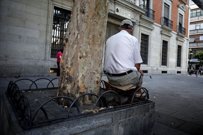 Un hombre descansa en la plaza Jacinto Benavente de Madrid, sobre un asiento improvisado con un trozo de cartón.