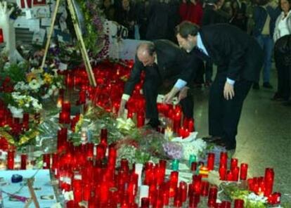 Eduardo Portela y Jaime Lissavetzky depositan un ramo de flores en la estación de Atocha.