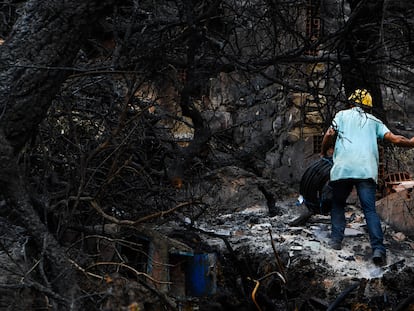 Un operario camina entre los escombros de una casa calcinada en Melloula (Argelia), este miércoles.