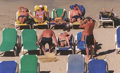 Un grupo de turistas toma el sol en una playa de Ibiza.