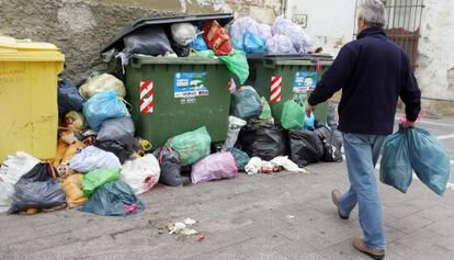 Un hombre se dirige a depositar dos bolsas de basura en una calle de Jerez.