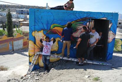 Vecinos de El Maclovio ayudan a Libre Gutiérrez a pintar con spray junto a La Gallera.