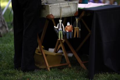 Tres marionetas cuelgan de una maleta durante una representación.
