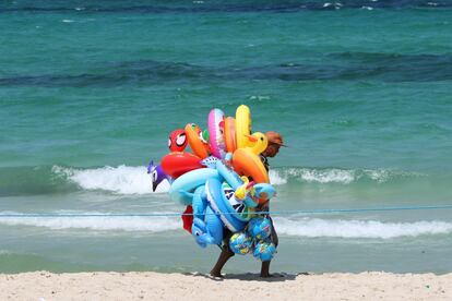 Un vendedor de playa camina por la playa en Sousse (Túnez).