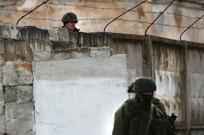 Militares rusos vigilan en el exterior de la base militar de la ciudad de Perevevalne en Crimea.