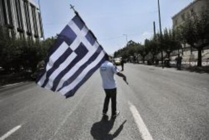Un policía municipal griego sujeta una bandera nacional, en una protesta frente al Parlamento de Atenas, el pasado julio.