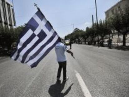 Un polic&iacute;a municipal griego sujeta una bandera nacional, en una protesta frente al Parlamento de Atenas, el pasado julio. 