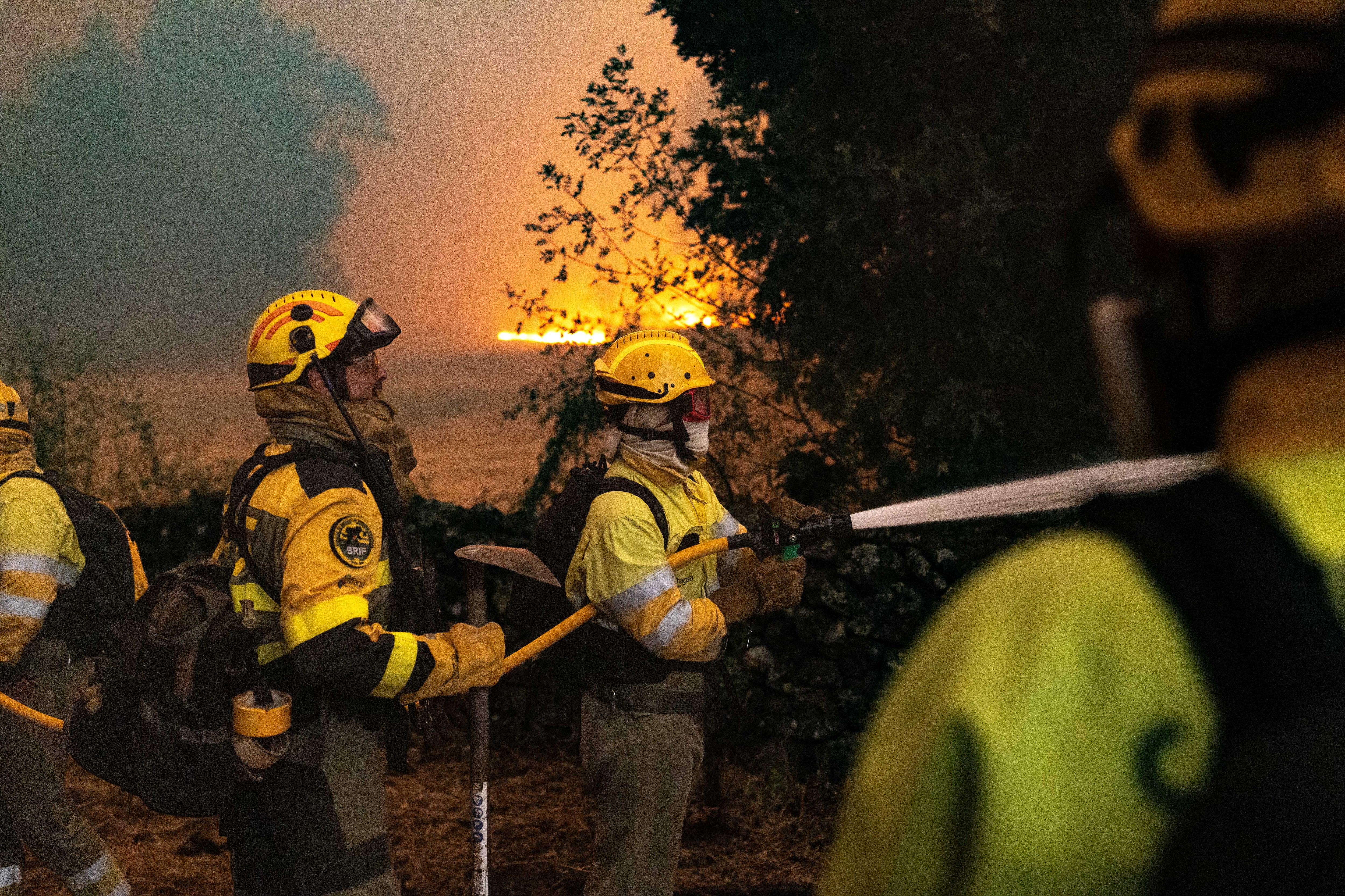 Los bomberos forestales refrescan la zona ante la inminente llegada del fuego a Casavieja, en la provincia de Ávila.