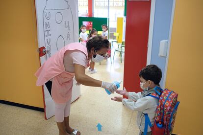 Una profesora echa gel hidroalcohólico en manos de un niño antes de entrar a su clase en Canarias.