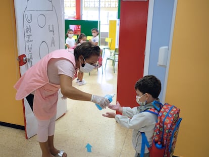 Una profesora echa gel hidroalcohólico en manos de un niño antes de entrar a su clase en Canarias.
