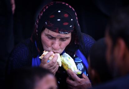 Una mujer come un trozo de pan mientras espera en un control camino de Erbil, capital del Kurdistán iraquí. Medio millón de ciudadanos se han visto obligados a abandonar sus casas por la toma por parte de los rebeldes de la ciudad de Mosul, según la ONU.