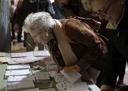 Una mujer busca la papeleta de la formación a la que va a votar en Pamplona.