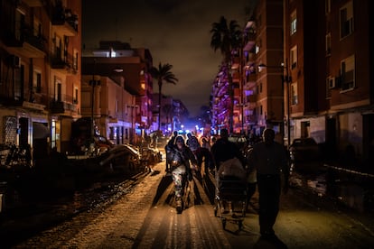 Grupos de vecinos recorren las calles de Paiporta al anochecer para reparartir alimentos, agua y productos de primera necesidad entre los habitantes de Paiporta, jueves 31 de octubre de 2024.