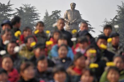 Varias personas posan para una fotografía delante de la estatua gigante del fallecido presidente de China, Mao Zedong durante una ceremonia para celebrar el próximo 120 aniversario del natalicio de Mao, en una plaza en Shaoshan.