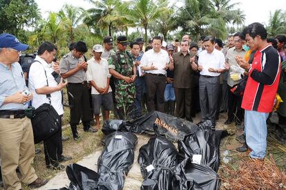 El vicepresidente indonesio, Boediono, reza delante de unos cadáveres,víctimas del maremoto que ha asolado la localidad de Muntei Baru Baru.