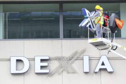 Los trabajadores retiran el logo del banco Dexia de la sede de la entidad en Bruselas, Bélgica. EFE/Archivo