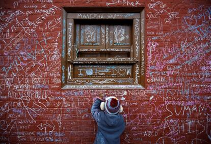 Un niño escribe con tiza en una pared para celebrar el festival Shreepanchami, en un templo de Katmandú (Nepal).