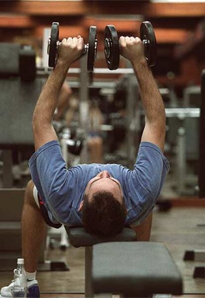 Un joven hace ejercicios con pesas en un gimnasio.