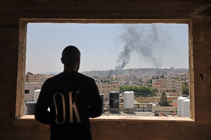 Un hombre palestino observa desde una ventana el humo tras los bombadeos del ejército de Israel. 