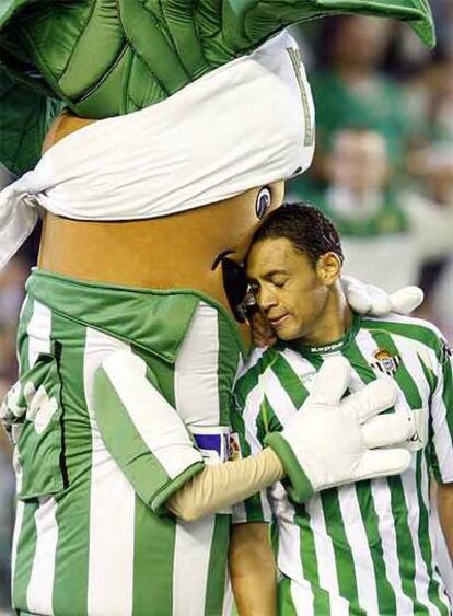 La mascota del Betis consuela a Oliveira tras el partido.