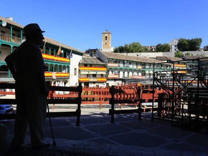 Un vecino en la plaza Mayor de Chinchón, adornada con banderas de España.