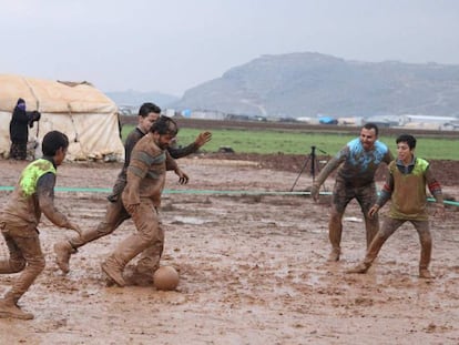 Un grupo de sirios desplazados por la ofensiva contra la provincia rebelde de Idlib (noroeste) juegan este jueves al fútbol en un campo embarrado en Sarmada.