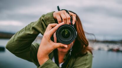 Una mujer tomando una foto en formato vertical con una cámara réflex.
