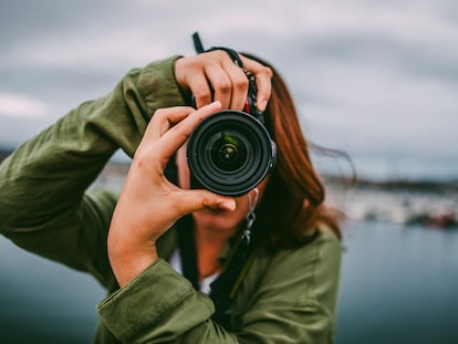 Una mujer tomando una foto en formato vertical con una cámara réflex.