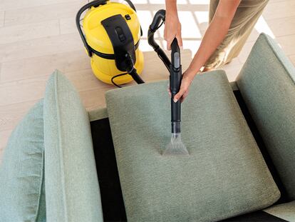 Una persona aspirando el sofá en su casa.