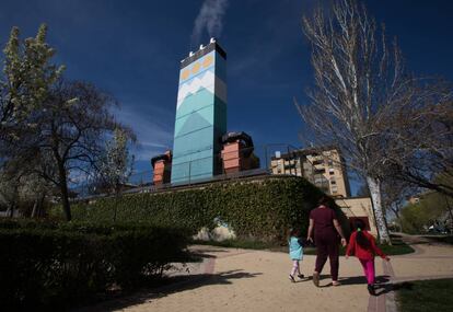 Una mujer pasea junto con sus hijas al lado de la central térmica autogestionada de Orcasitas, en Usera (Madrid).