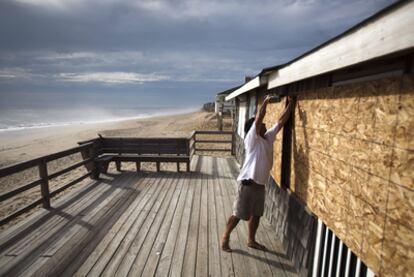 Un hombre coloca tablones de madera para proteger una casa ante la llegada del huracán Irene, en Kitty Hawk (Carolina del Norte).