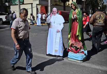 Un hombre pasa delante de una imagen del papa Francisco y una estatua de la Virgen María en Ciudad de México.