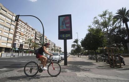 Ciclista passa em frente a um termômetro que marca 50ºC em Córdoba