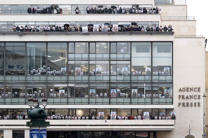 Empleados de Agencia France Presse posan en las ventanas de la sede de la agencia en París sosteniendo retratos en apoyo a los periodistas de AFP que trabajan en la Franja. 