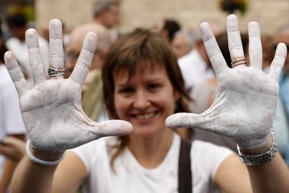 Una mujer con las manos pintadas de blanco se manifiesta frente al Ayuntamiento de Barcelona.