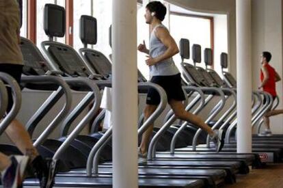 Cliente de un gimnasio escucha música mientras corre en la cinta.