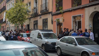En primer plano, un grupo de vecinos intenta aplazar el desahucio de Marina López; de fondo, unas 40 personas bloquean la entrada al edificio donde vive la inquilina.