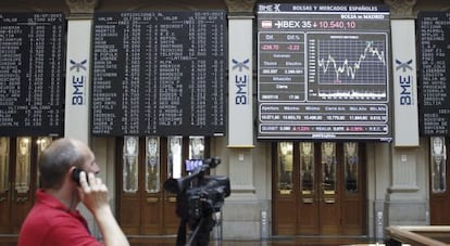 Un càmera davant d'un panell informatiu de la borsa de Madrid.