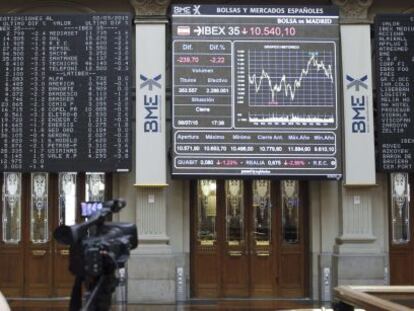 Un càmera davant d'un panell informatiu de la borsa de Madrid.