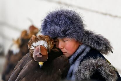 Un joven cazador descansa junto a su águila dorada durante un concurso de cazadores en el hipódromo de Almaty (Kazajistán), el 9 de febrero de 2018.