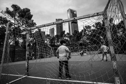 Unos chicos juegan al fútbol en un parque del barrio de La Ventilla, con las torres de plaza de Castilla al fondo.