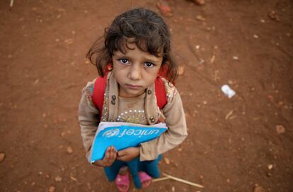 Una niña sostiene un libro antes de entrar a la escuela, en el campo de desplazados de al-Jeneinah, al norte de Ia provincia de Idlib (Siria).