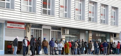 Varias personas forman una larga cola ante una oficina de empleo.